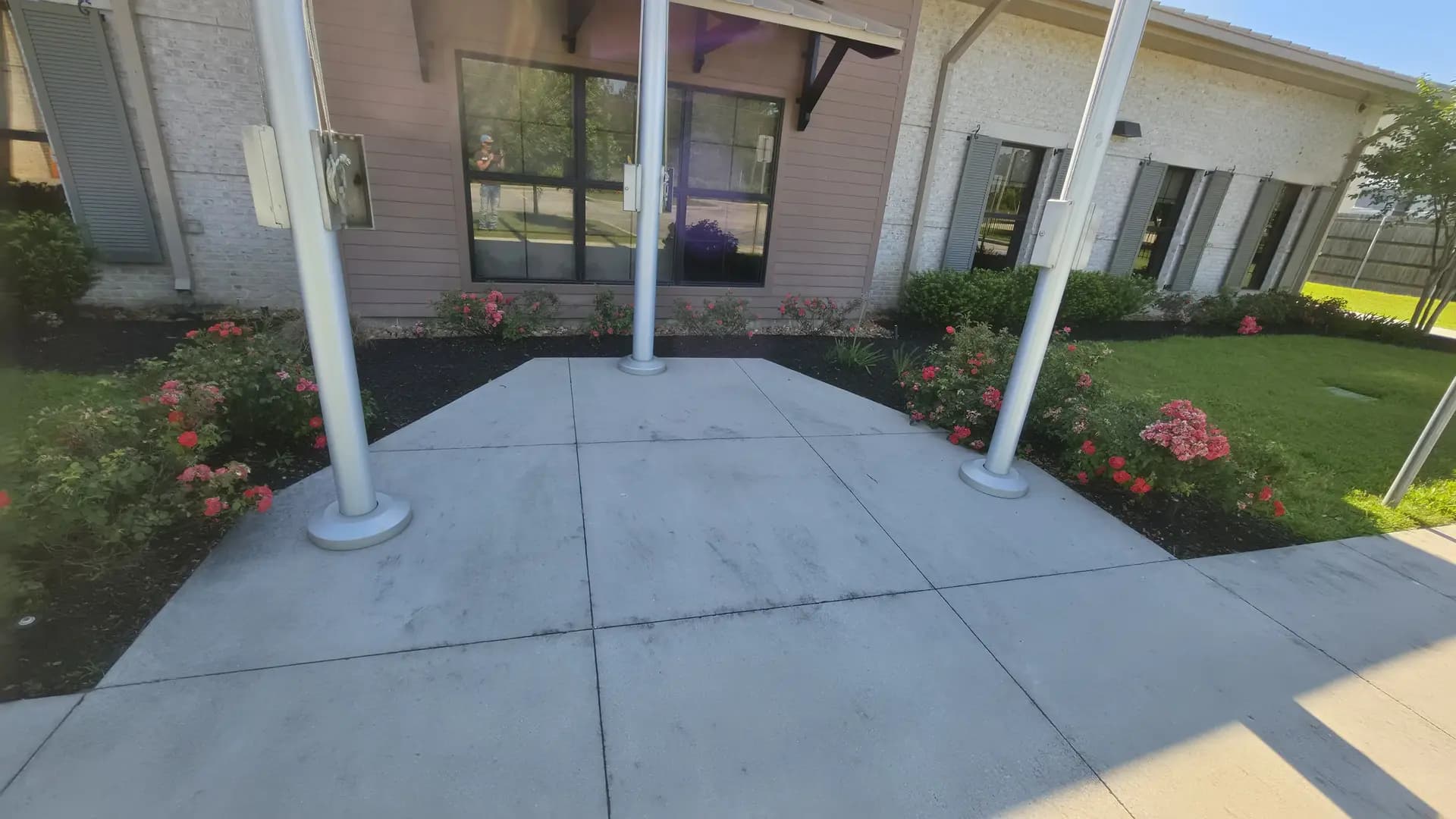 Commercial front entrance with fresh black mulch, roses, and flagpoles maintained by Southern Buck Lawn in Livingston, LA