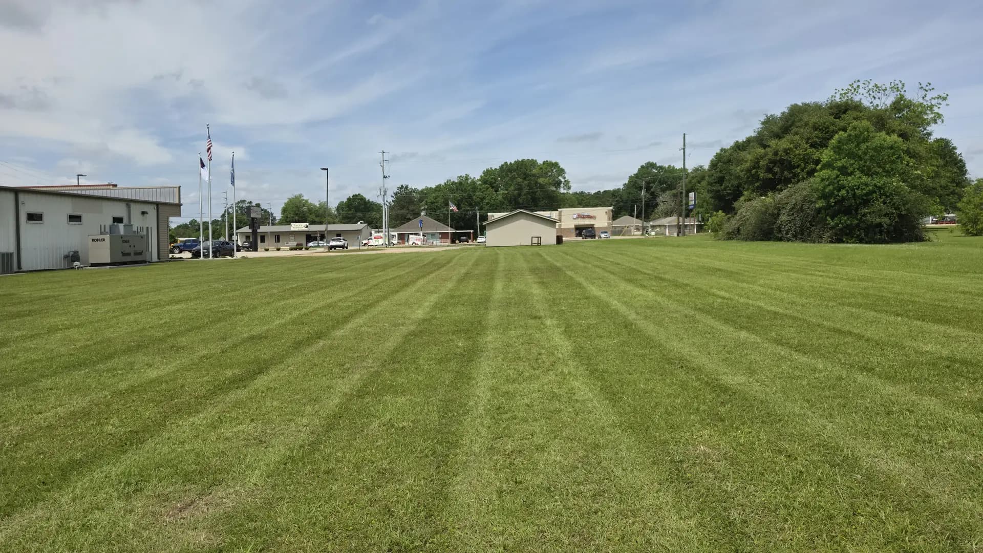 Wide green lawn cut with clean mowing stripes at the correct summer height in Louisiana