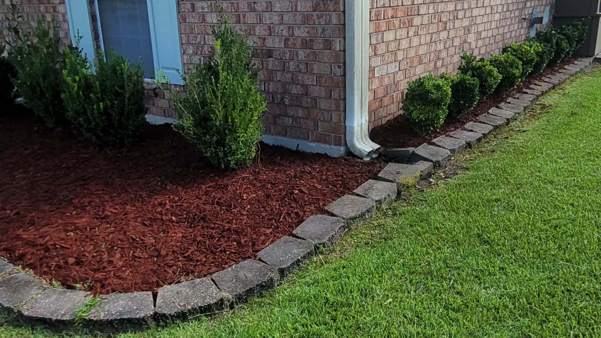 Fresh mulch bed, stone border, and healthy green lawn by Southern Buck Lawn in Denham Springs, Louisiana