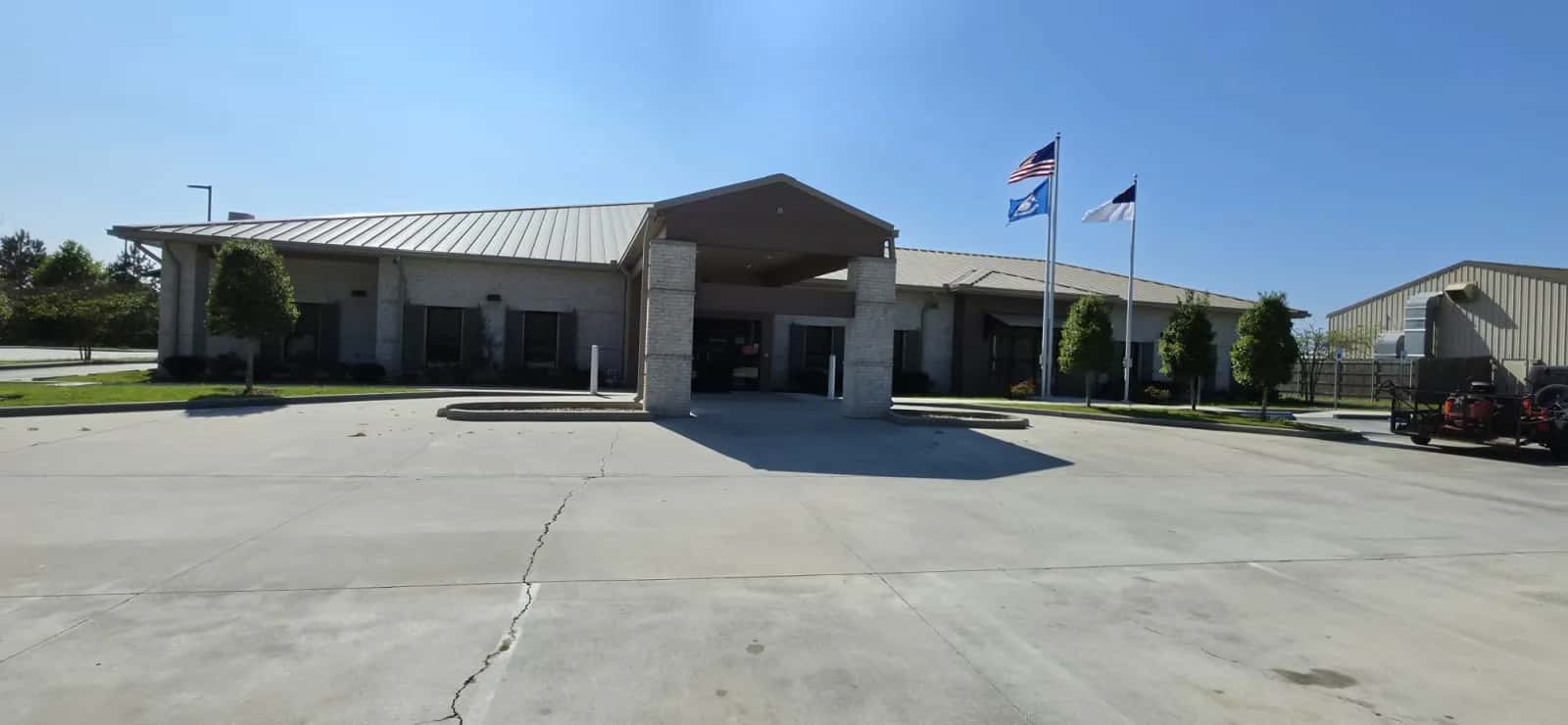 Maintained commercial building lawn and beds with Southern Buck Lawn trailer and zero-turn in view.